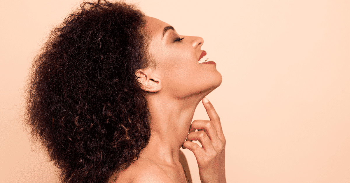 a stunning curly woman pointing her finger to her chin
