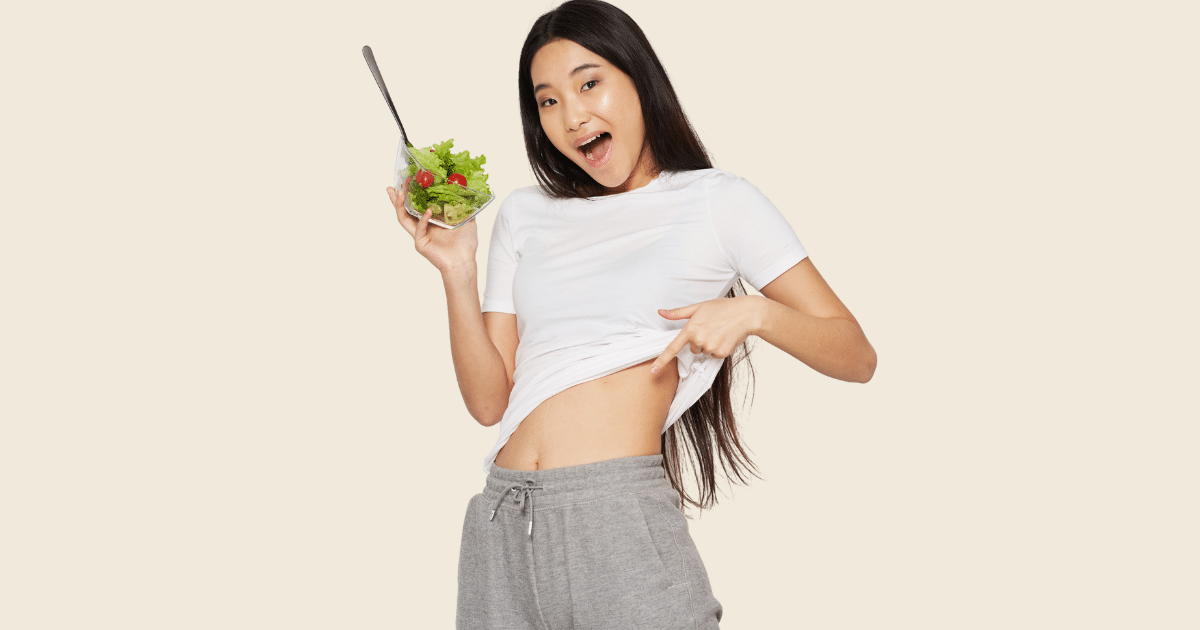 a woman displaying her trim waist while holding a salad in her right hand