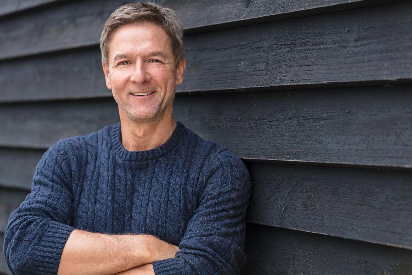 Man wearing a dark blue sweater smiling.