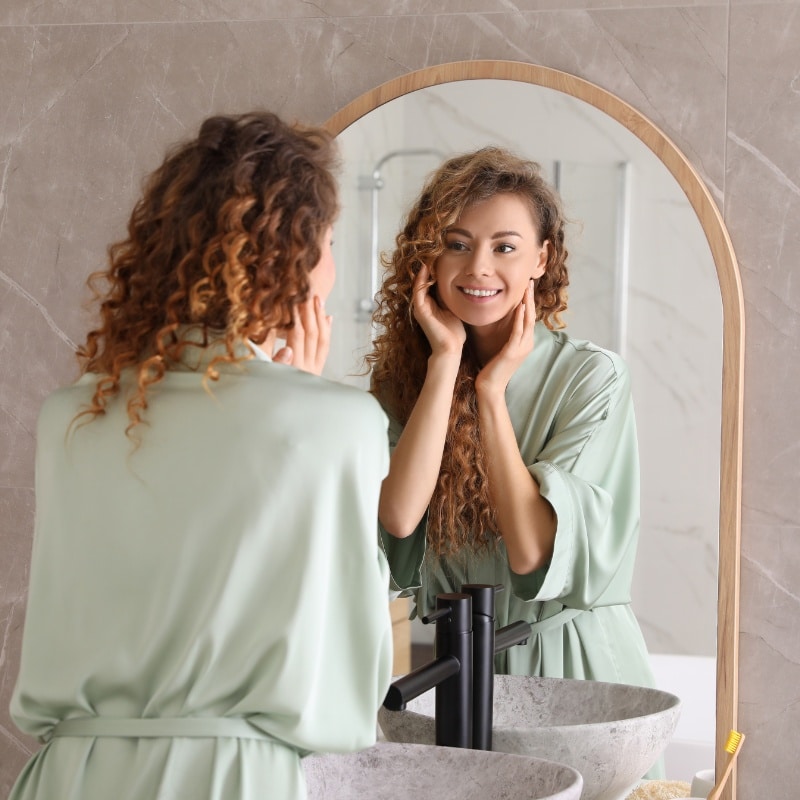 woman smiling her reflection in the mirror